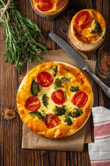 Vegetable pie with broccoli, peas, thyme. tomatoes and cheese on wooden background. Copy space.