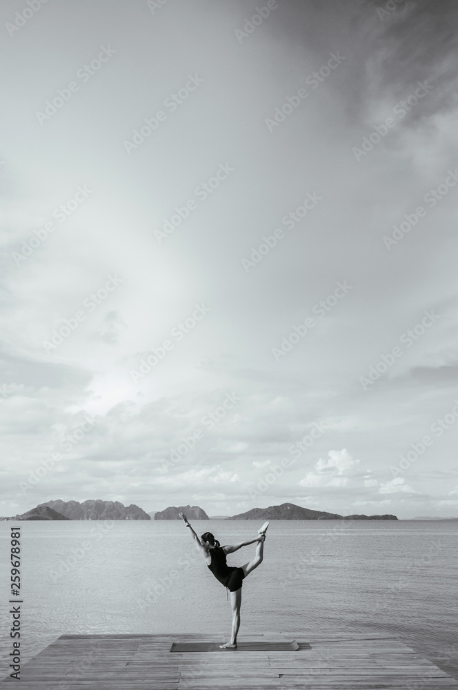 Wall mural Asian woman doing yoga on the wooden pier by the sea. Koh lanta, Krabi, Thailand