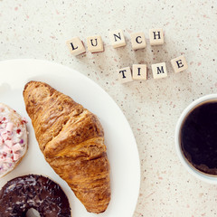 plate of baked sweets cup of coffee and lunch time letters on wooden bloks square