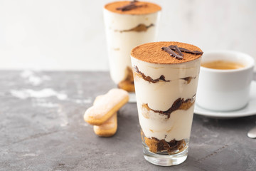 Tiramisu in a glass with coffee beans on grey background. Copy space. Selective focus.