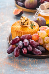 Naklejka na ściany i meble Cheese plate served with grapes, jam, figs, crackers and nuts on a background.