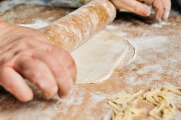 Obraz premium Men's male hands roll out the dough: flour everywhere, ready-made slices of dough