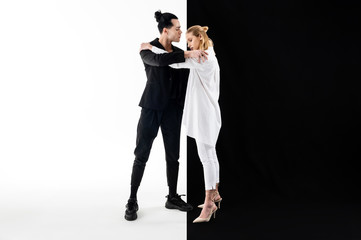 Models wearing white and black clothes hugging while posing