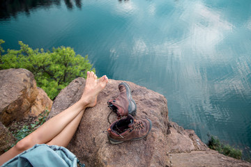woman hiker at mountain peak relaxing barefoot near mountain lake