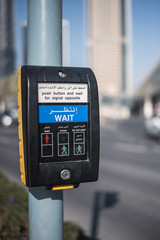 A device with a traffic light control button for pedestrians shows a red and two green men