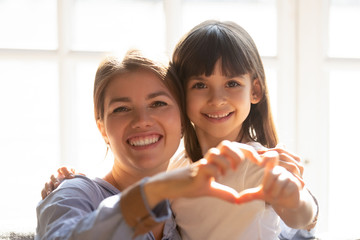 Headshot portrait mother and daughter make heart shape with hands