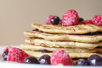 Vegan breakfast. Closeup of homemade buckwheat pancakes sprinkled with raspberries and blueberries. Healthy gluten free dessert. Eat well concept.