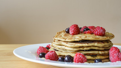 Vegan breakfast. Closeup of homemade buckwheat pancakes sprinkled with raspberries and blueberries. Healthy gluten free dessert. Eat well concept.