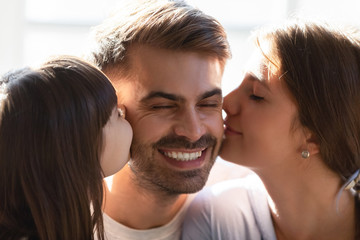 Little daughter and loving wife kissing father husband