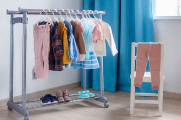 Children's cloth rack, selective focus. Pastel color children's  clothes in a Row on Open Hanger...