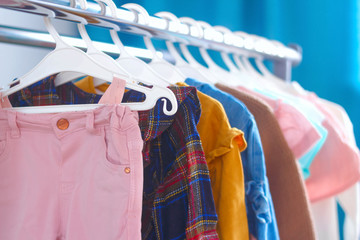 Children's cloth rack, selective focus. Pastel color children's  clothes in a Row on Open Hanger indoors. Clothes for little ladies hung in the children's room. Turquoise and pastel pink colors.