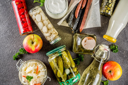Assortment of various fermented food - apple cider vinegar, fermented meat and vegetables, sauerkraut, pickled peppers, tomatoes, garlic, capers, black background copy space