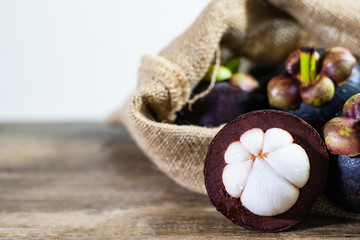 cross section show white flesh of mangosteen in gunny sack on wood table texture with copy space