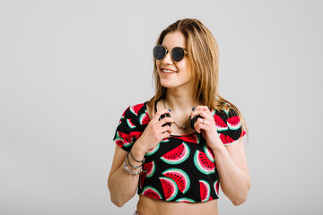 Young caucasian woman in sunglasses with headphones posing on grey background