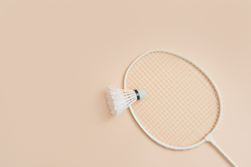 Shuttlecock and racket for playing badminton on a cream background. Concept summer game