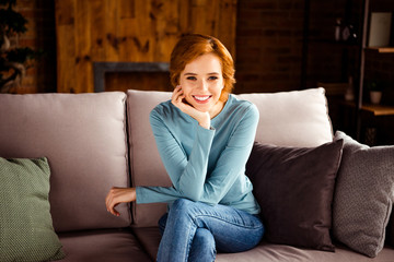 Fototapeta premium Close up photo amazing beautiful she her lady leaning chin hand palm arm white teeth red short hairdo wear blue pullover jeans denim clothes sit comfortable divan house loft living room indoors