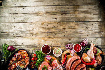 Various raw meat ready for grill and bbq, with vegetables, greens, sauces kitchen grilling...