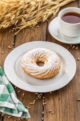 Cream puff rings with powdered sugar choux pastry on wooden table