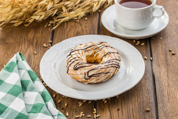 Cream puff rings with chocolate glaze choux pastry on wooden table