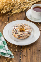 Cream puff rings with chocolate glaze choux pastry on wooden table