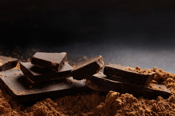Macro shot of dark chocolate pieces and ccocoa on black background.
