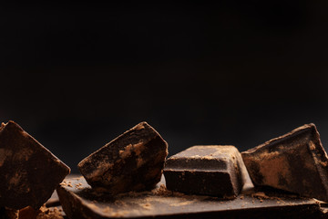 Pieces of chocolate and cocoa on dark background. Close up.