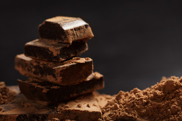 Pieces of chocolate and cocoa on dark background. Close up.