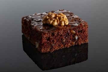 Chocolate cake with walnuts on a black background with reflection