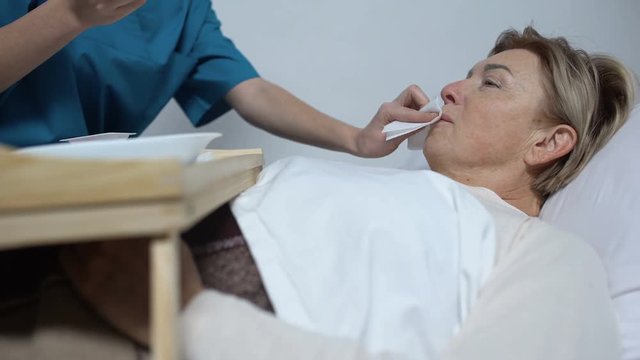 Nurse feeding disabled mature woman with porridge, care for patients, hospice