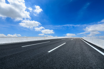 Fototapeta premium Empty asphalt road and blue sky with white clouds scene