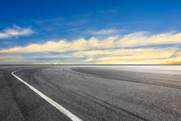 Naklejka premium Asphalt race track ground and beautiful sky clouds at sunset