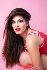 Fototapeta premium Cute Sexy Girl - Brunette In A Red Swimsuit Posing On A Pink Background
