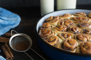 Cinnamon roll tart with sugar syrup in vintage baking pan on black background
