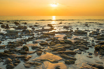 Fototapeta na wymiar Beautiful colorful sunset landscape with sand beach, golden sun and stones at sea shore