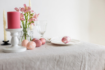 Fototapeta na wymiar Easter table set on linen tablecloth with Easter egg on plate with decor.