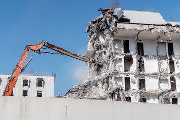 excavator-destroyer breaks the wall of the building. demolition and dismantling of the town house