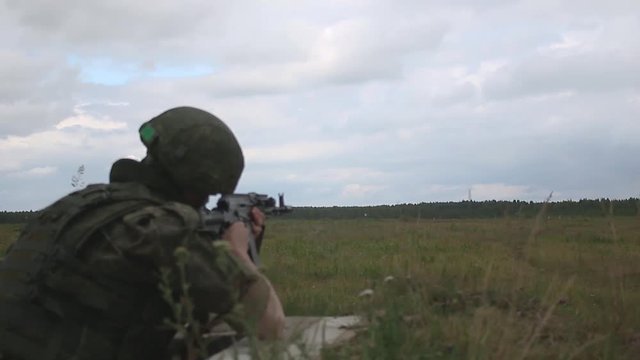 Russian soldier in armor and helmet firing a machine gun. Soldier shoots AK 74m