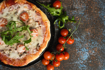 Pizza with ham and rocket on dark ground
