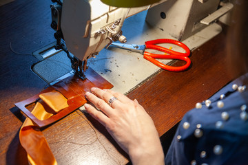 Young girl tailoring  on the sewing machine.  Leather wallet