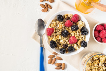 Organic granola with fresh berries , jam and cashew nuts on white background flat lay.
