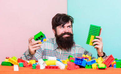 Still child in his soul. Man bearded hipster play plastic bricks. Create construction blocks. Colorful details. Build constructions. Guy happy face play constructor. Create funny constructions