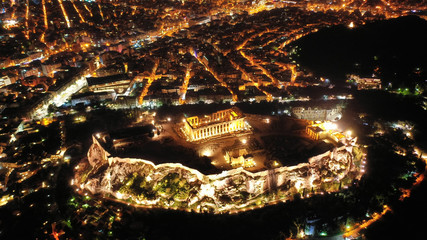 Aerial drone night shot of iconic illuminated landmark Acropolis hill and the Masterpiece of Ancient times and Western civilisation - the Parthenon, Athens historic centre, Attica, Greece
