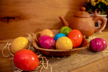 Colorful easter eggs on a basket in wooden surrounding background
