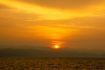Fototapeta premium Golden light of sunrise behind the mountains and the sea.