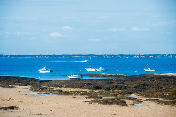 Boat on the beach of le plage du petit vieil at Noirmoutier in summertime with people fishing in the background