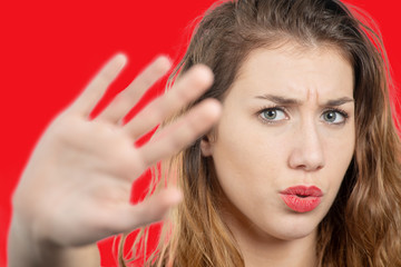 Fototapeta premium Portrait of a beautiful girl showing stop sign with palm