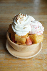 Homemade Toasted Bread with Vanilla Ice Cream, strawberry Topping with Whip-Cream, Pecans in Wooden Bowl.