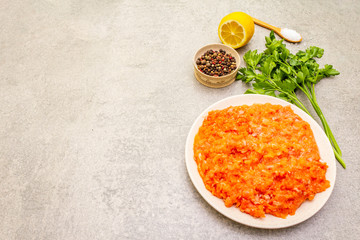 Raw minced red fish (stuffing) on a stone background. Ingredient for making fish-balls, casseroles, terrine, pate. Spices, salt, parsley, lemon. On a stone background, copy space.