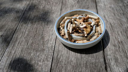 Cigarette in ashtray on wooden background.