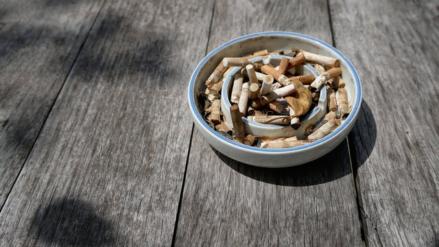 Cigarette in ashtray on wooden background.